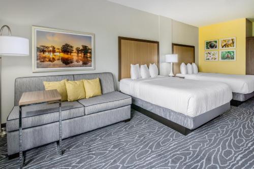 a hotel room with two beds and a couch at La Quinta Inn & Suites by Wyndham Valdosta in Valdosta