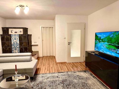 sala de estar con sofá y TV de pantalla plana en Wie Zuhause! Wohnung mit Garten, en Forstinning