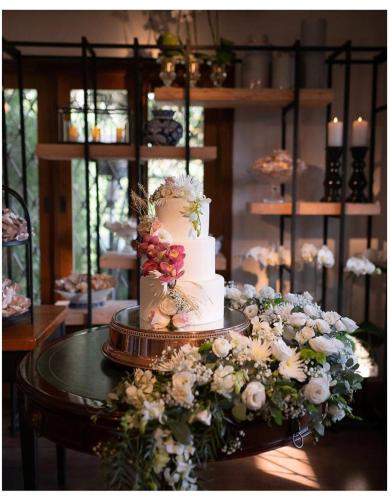 a white wedding cake sitting on a table with flowers at Pousada das Lavandas in Campos do Jordão
