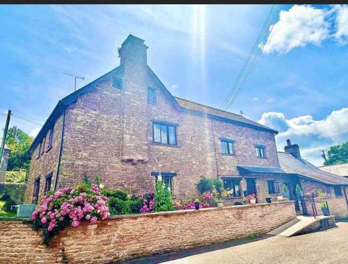 an old brick building with flowers in front of it at 16th Cent,6 bed house,15 People in Llangwm-isaf