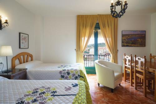 a bedroom with two beds and a chair and a window at Doña Ruidera in Ruidera