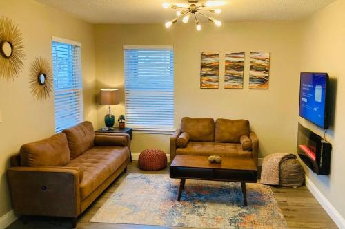 a living room with a couch and a tv at Pensa-Cozy Downtown bungalow, w/ backyard oasis! in Pensacola