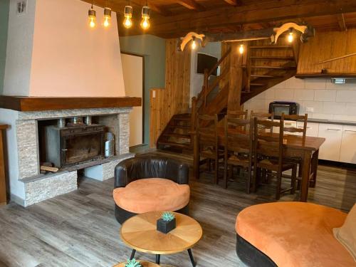 - un salon avec une cheminée, une table et des chaises dans l'établissement Maison de montagne, à Auzat