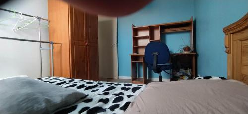 ein Schlafzimmer mit einem Bett und einer blauen Wand in der Unterkunft Chez Laurent in Mérignies