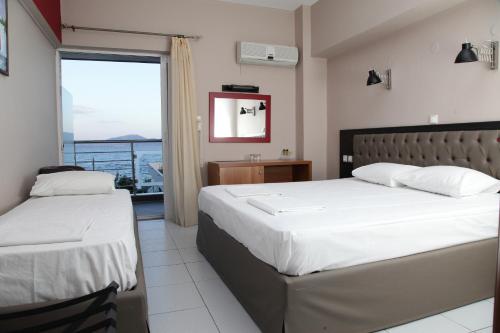 two beds in a bedroom with a view of the ocean at Evvoiki Akti Hotel in Politika