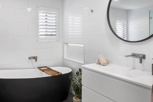 een badkamer met een bad, een wastafel en een spiegel bij Rengor Executive Retreat in Belmont