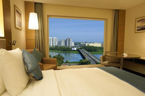 a hotel room with a large bed and a large window at Gokulam Grand Trivandrum in Trivandrum
