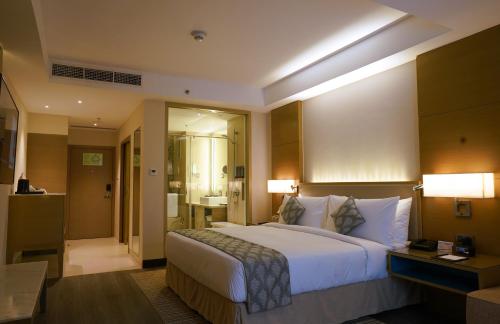 a hotel room with a large bed and a bathroom at Gokulam Grand Trivandrum in Trivandrum