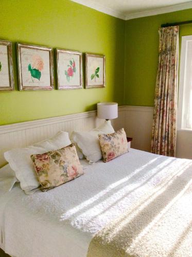 a bedroom with green walls and a bed with pillows at Hotel El Ciervo in Villarrica