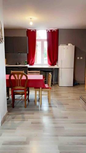 La cuisine est équipée d'une table et de chaises rouges ainsi que d'un réfrigérateur. dans l'établissement Location duplex tout confort, à Erquinghem-Lys