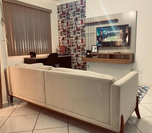 ein Wohnzimmer mit einem Sofa und einem Flachbild-TV in der Unterkunft APTO - Espaço Village Completo - 2Q in Vitória