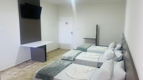 a small room with two beds and a desk at Hotel Tenda Diadema in Diadema