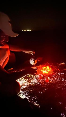 uma pessoa está olhando para um fogo no escuro em Starlight Camp Nuweiba em Wāsiţ