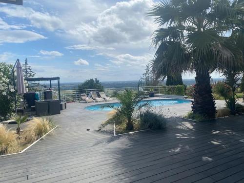 - une piscine avec des chaises et un palmier dans l'établissement Maison vue panoramique et accès SPA, à La Réole
