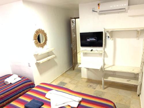 a room with a bed and a tv in a room at Maria Flor Pousada in Taíba