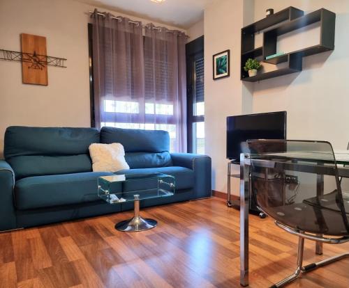 a living room with a blue couch and a glass table at Apartamento El Estrecho in Algeciras