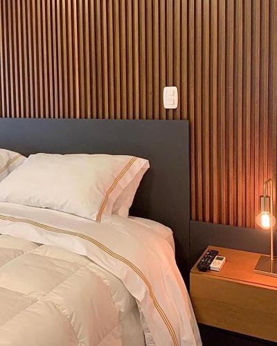 a bedroom with a bed and a table with a lamp at Austin Suites Gramado in Gramado