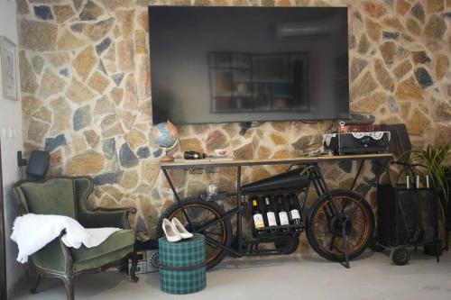a bike parked in front of a stone wall with a television at Laethos in Kfar Yona