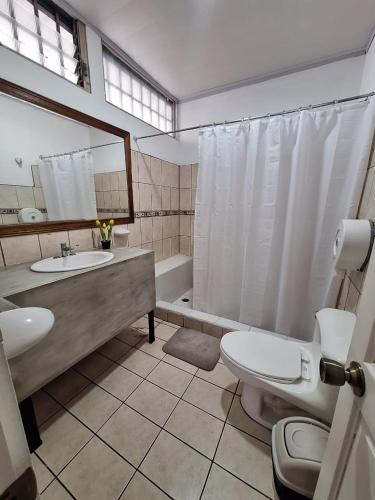 a bathroom with a sink and a toilet and a tub at Gaudy's Hotel in San José