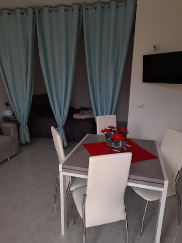 a dining room table with white chairs and a vase of flowers at Sognando nel borgo in Rocca Imperiale