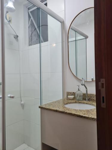 uma casa de banho com um chuveiro, um lavatório e um espelho. em Apto 300m da Oktuberfest em Blumenau
