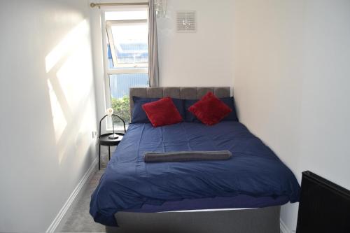 a bed with two red pillows in a room at Luxury Home Close to Leeds City Centre in Leeds