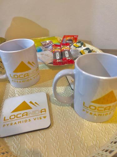 two coffee mugs sitting on top of a table at Locanda pyramids view in Cairo