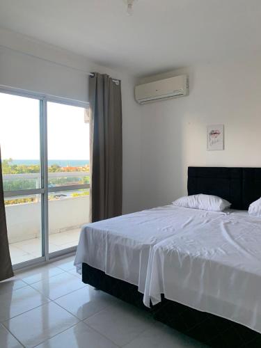 a bedroom with a white bed and a large window at Apartamentos Cumbuco Condomínio Vila Real in Caucaia
