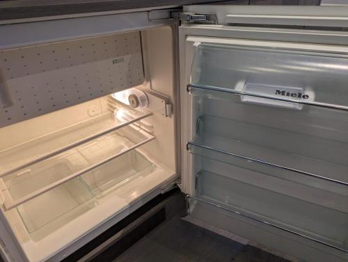 an empty refrigerator with its door open in a kitchen at Claresholm in Barnet