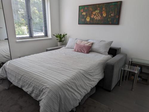 a bedroom with a bed with a pink pillow on it at Claresholm in Barnet