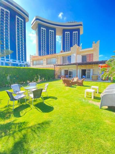 a lawn with chairs and a table in front of a building at فيلا للإيجار مارينا 7 الساحل الشمالي in El Alamein