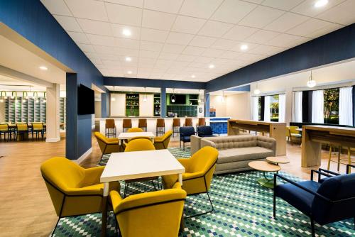 a waiting room with yellow chairs and tables at Sonesta Select Philadelphia Airport in Philadelphia