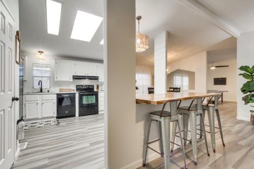 a kitchen with white cabinets and a bar with stools at Phoenix Family Home Near Cave Creek and Hiking! in Phoenix
