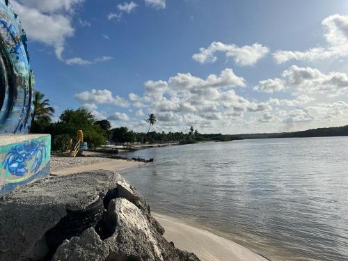 a person sitting on a beach next to a body of water at Condomínio Villa Sossego in Goiana