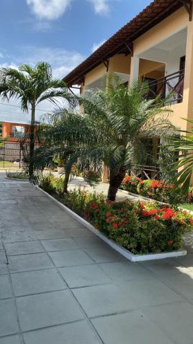 a building with palm trees and flowers next to a sidewalk at Condomínio Villa Sossego in Goiana