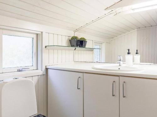 een witte badkamer met een wastafel en een raam bij Holiday home Jerup LX in Jerup