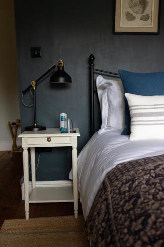 a bedroom with a bed and a table with a lamp at Saltmarsh Farmhouse in West Dean