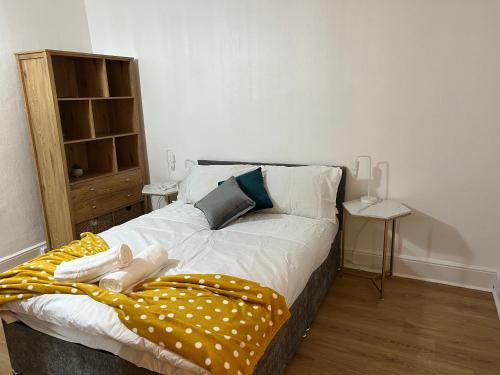 a bedroom with a bed with a yellow blanket at De Luxe Apartment in Leicester