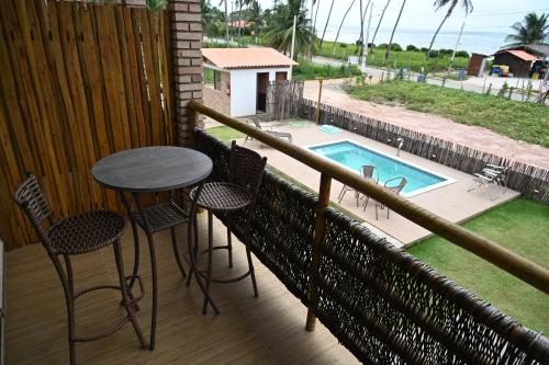 a balcony with a table and chairs and a swimming pool at Pousada Estação do Mar in Japaratinga