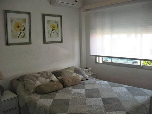 um quarto com uma cama com um cobertor xadrez e uma janela em Apartamento para familia o parejas em Punta del Este