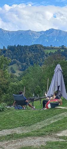 two people laying in chairs and a tent in a field at Touch the Sky in Moieciu de Jos