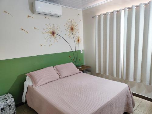 1 dormitorio con 1 cama y un mural de flores en la pared en Condomínio Capim Santo, en Goiânia