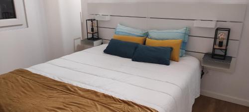 Una cama blanca con almohadas azules y amarillas. en Casa da Ponta Negra en Vila do Porto