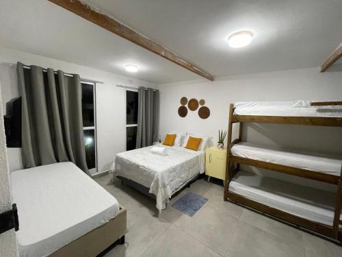 a bedroom with two bunk beds and a television at Blue Hale in Guarujá