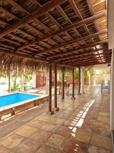 un patio al aire libre con piscina y techo de madera en Selenes Hostel en El Sargento