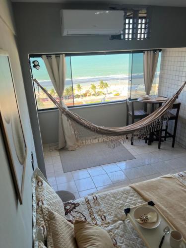 uma rede de descanso num quarto com vista para a praia em Flat privilegiado em Natal