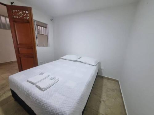 1 dormitorio con 1 cama con sábanas blancas y puerta en casa antioquia, en Circasia