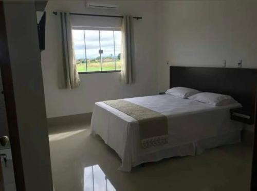 a white bedroom with a bed and a window at Hotel Cruzeiro de São José in São Francisco de Goiás