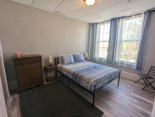 ein Schlafzimmer mit einem Bett, einer Kommode und zwei Fenstern in der Unterkunft Charming Apartments in the Heart of Robinson in Robinson