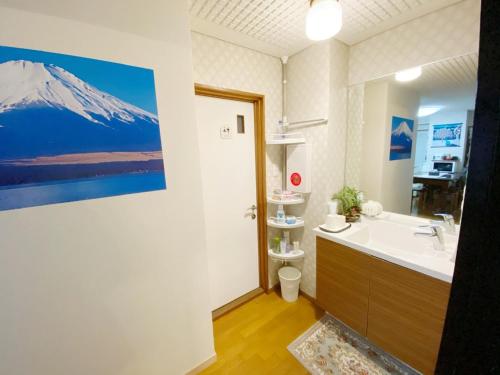 uma casa de banho com um lavatório e uma pintura de montanha na parede em Reinahill - Vacation STAY 67171v em Tokushima
